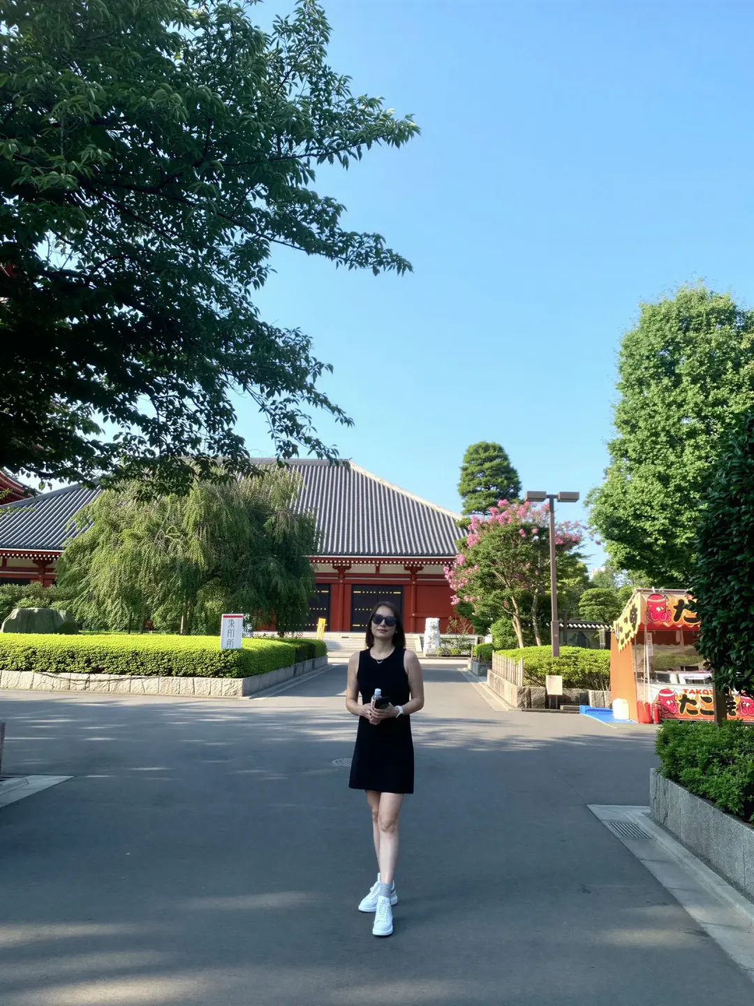 Alicia in a black mini dress walking through a quiet Tokyo temple